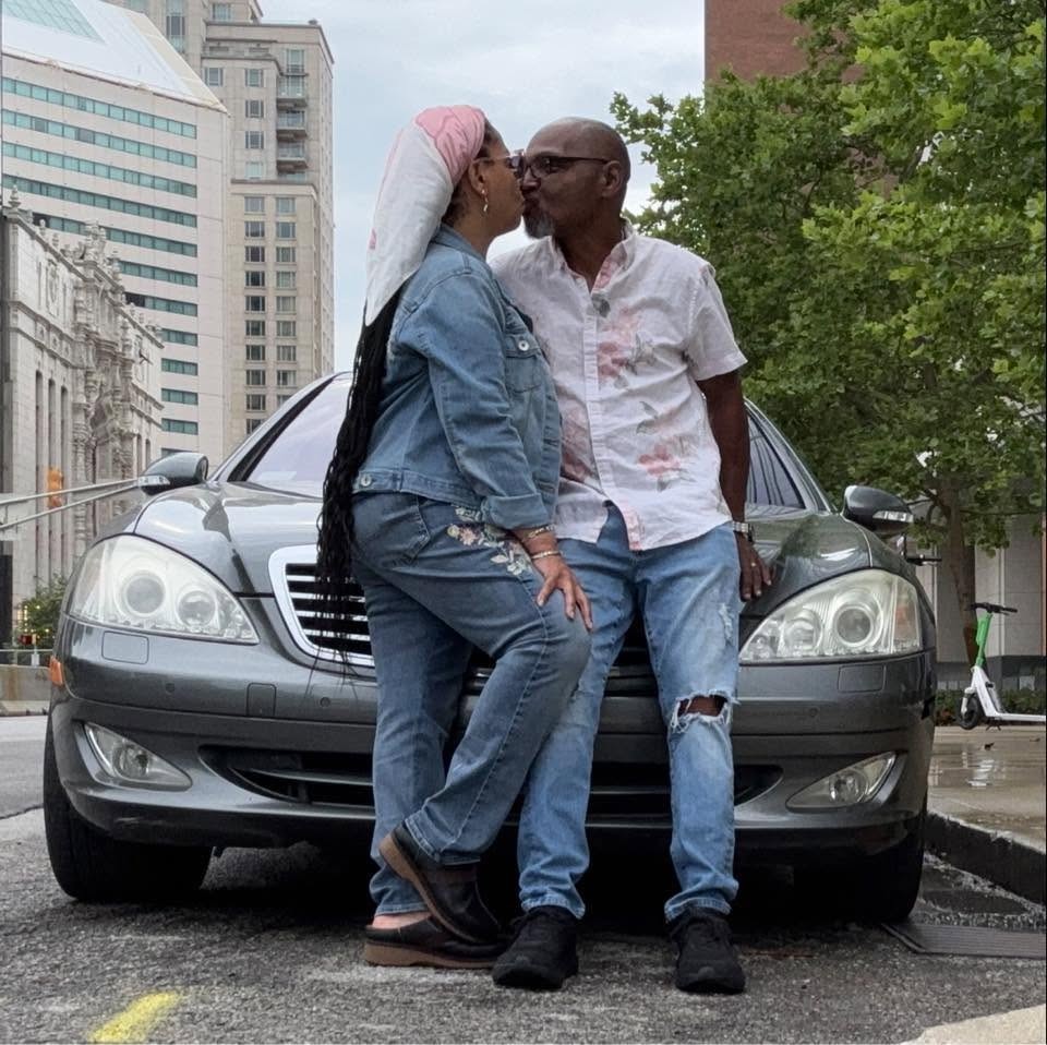 James and Shawn sharing an affectionate kiss beside a car